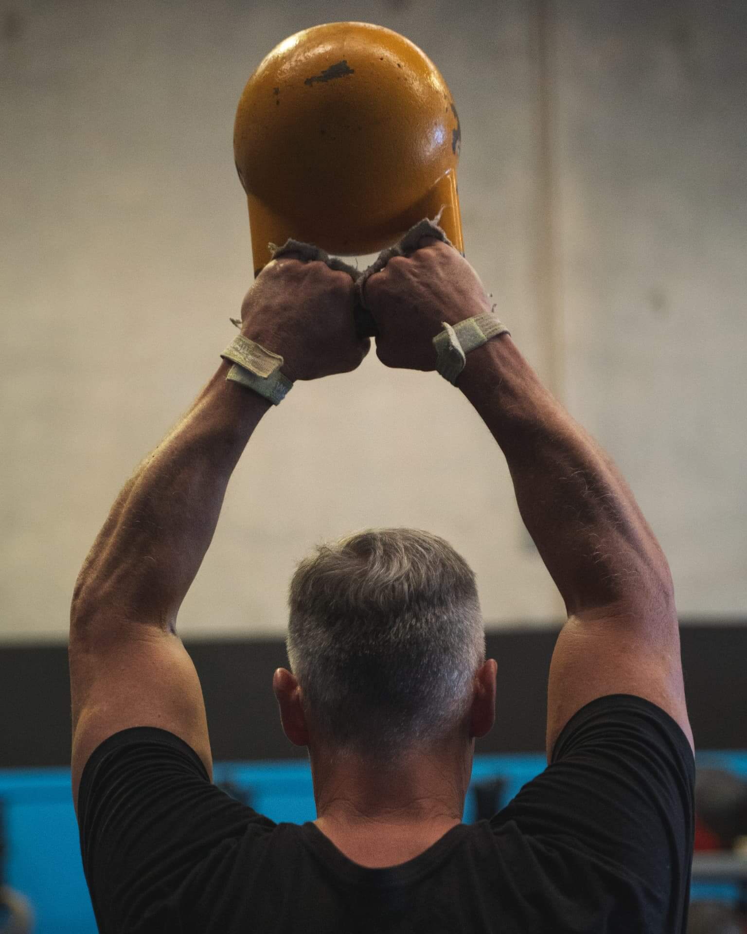 A long-time member pressing a kettlebell overhead