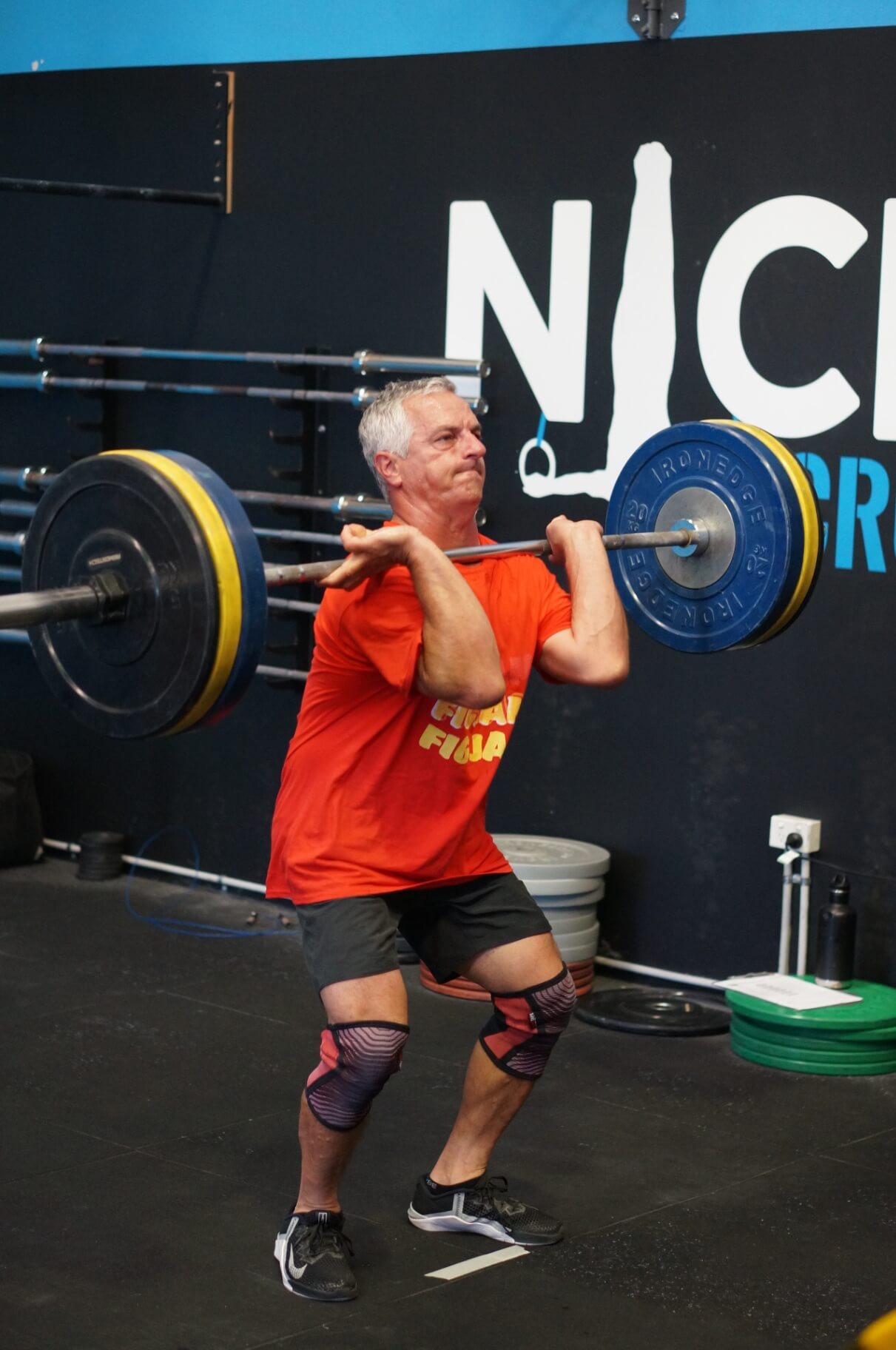 Member mid-lift in front of the Niche CrossFit logo