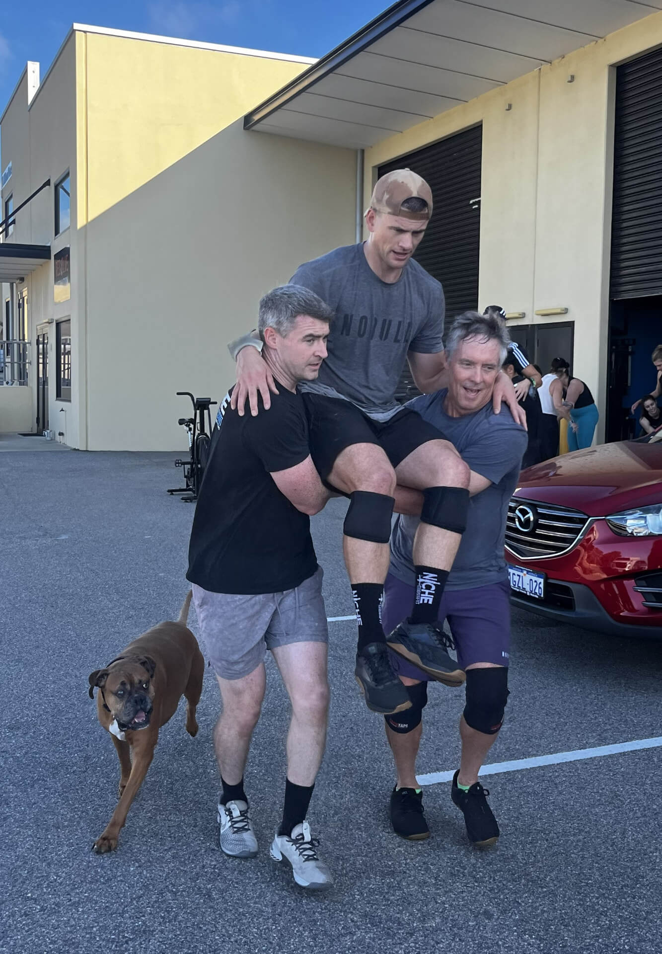 Members carrying a mate in the car park with the gym dog