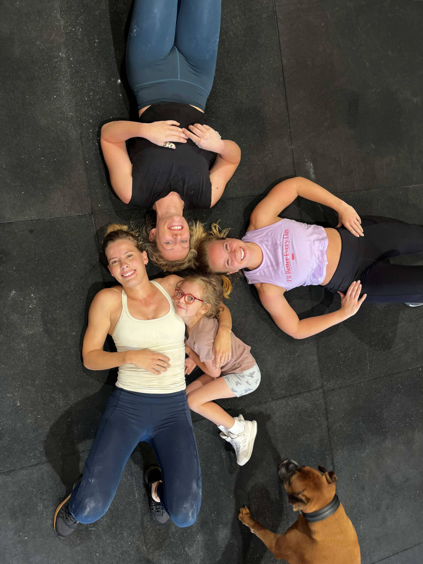 Members and a little one lying on the gym floor after class