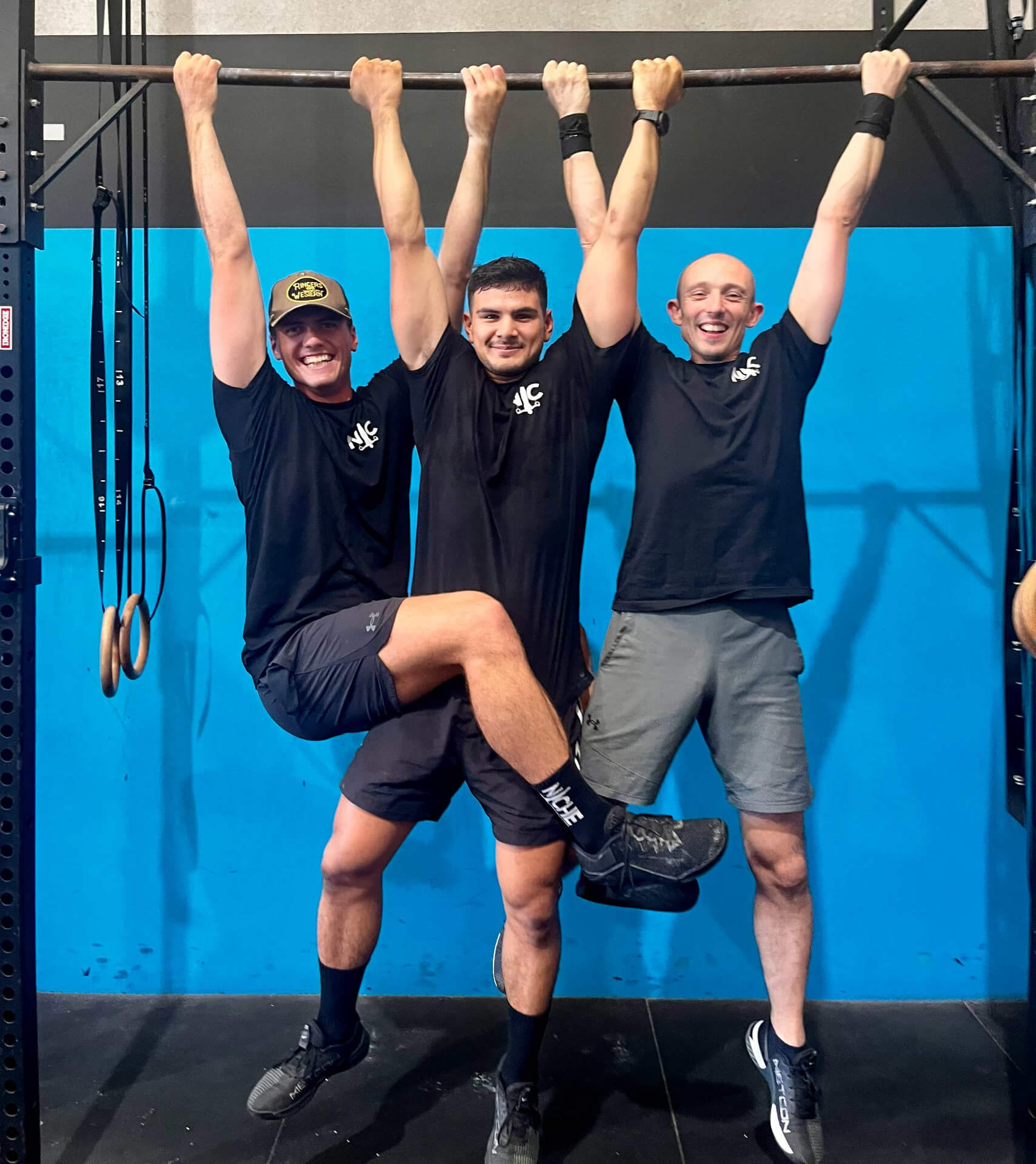 Three members hanging from the pull-up bar and laughing