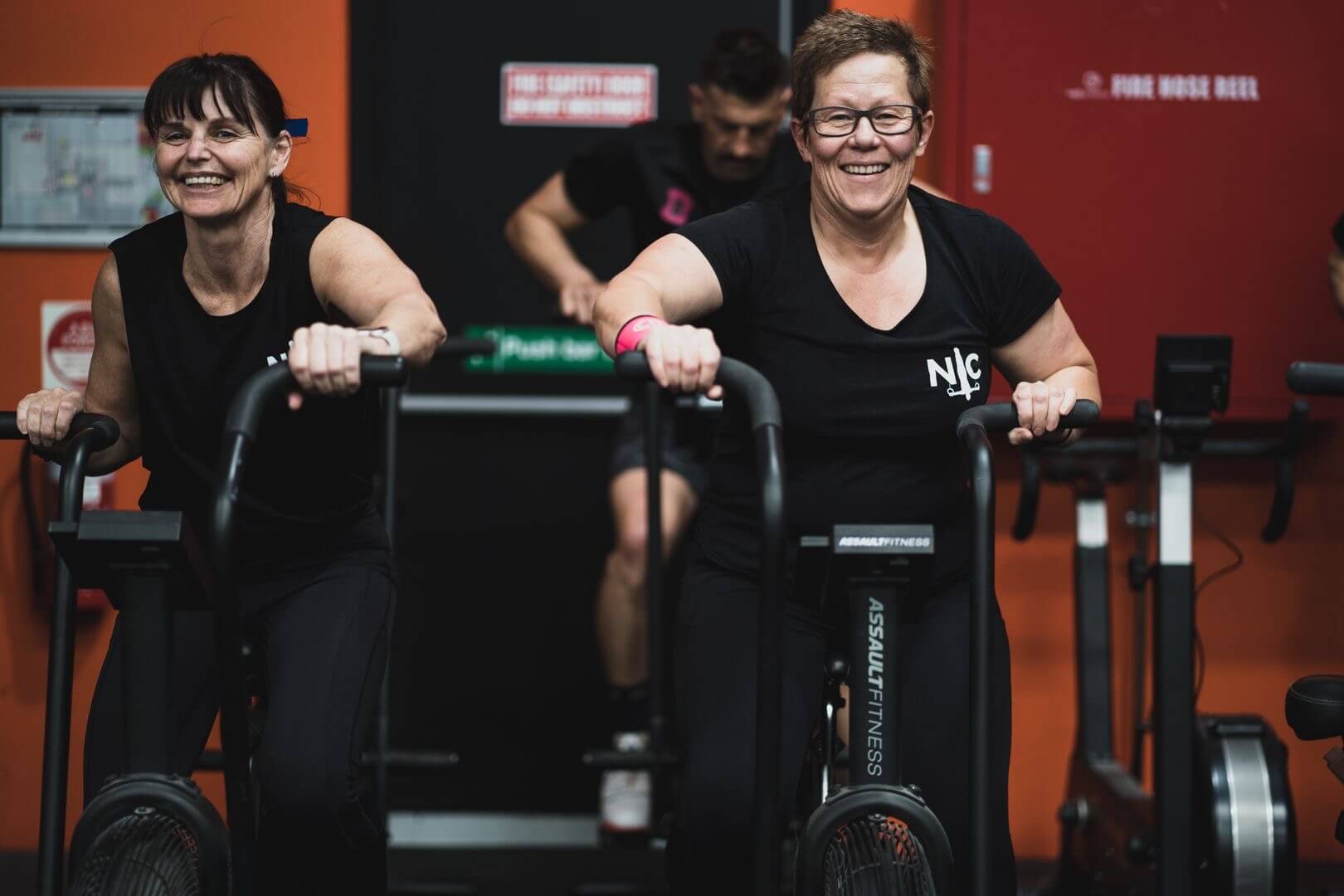 Members working hard side by side on the assault bikes