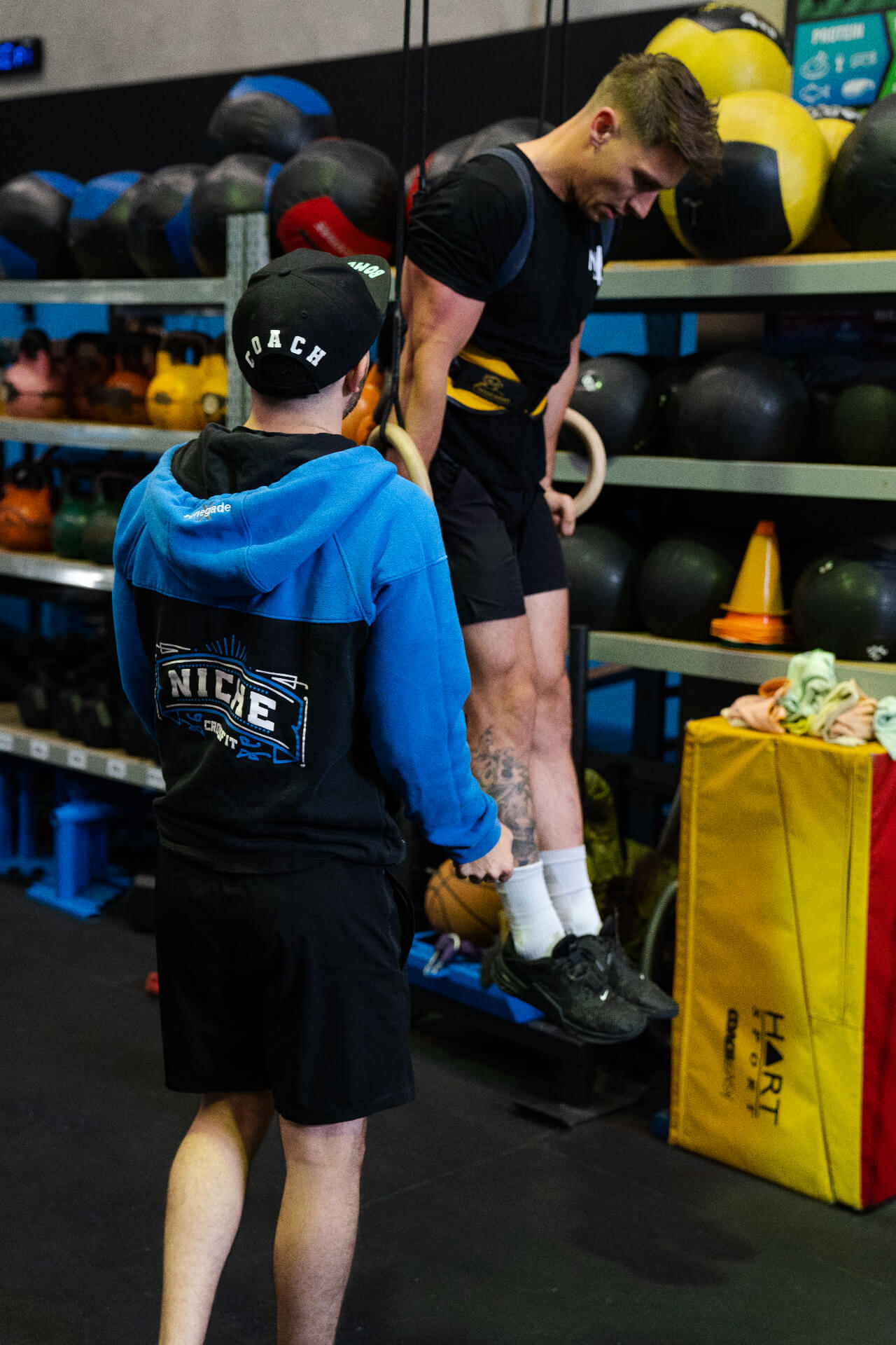 A coach spotting a member on ring dips