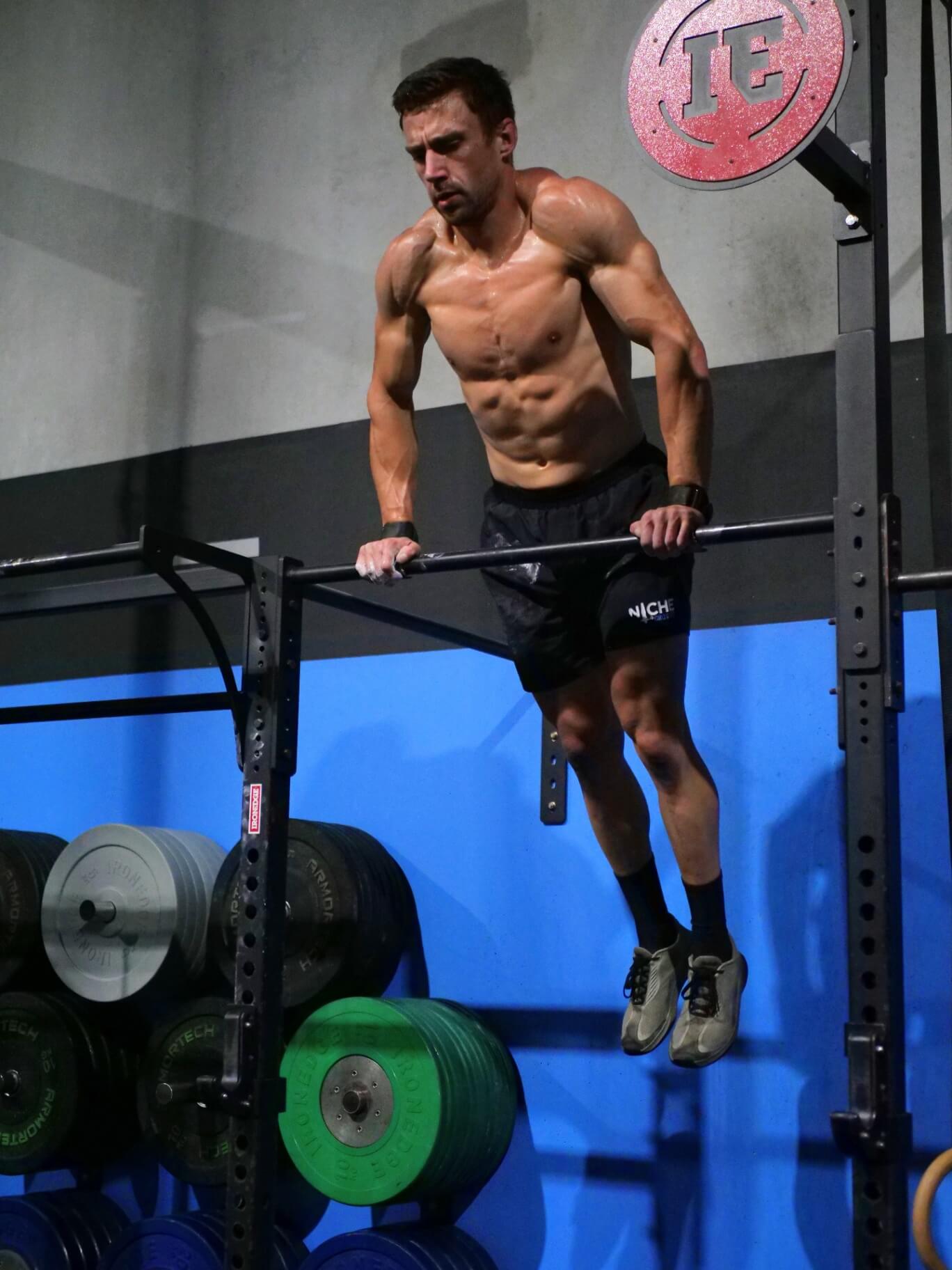 Member performing muscle-ups on the rig
