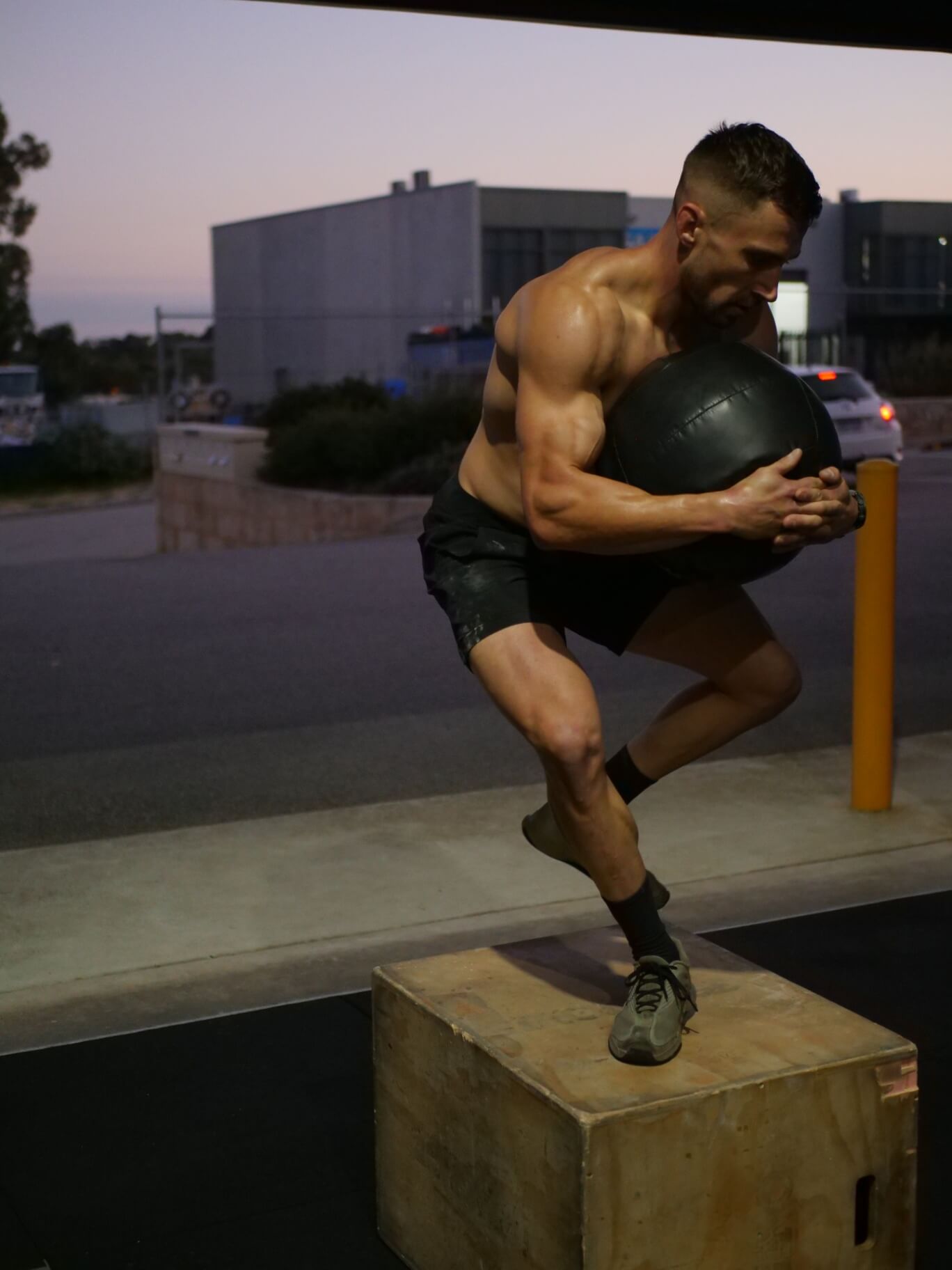 Member squatting to a box at sunrise