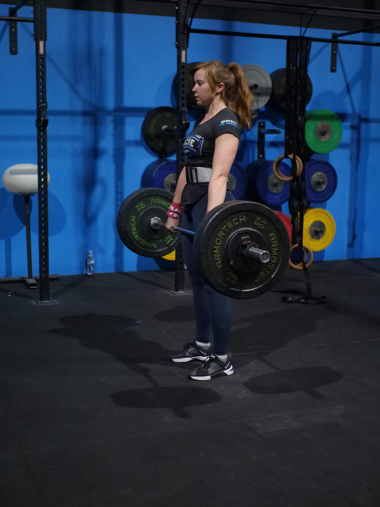 Member deadlifting in front of the blue wall