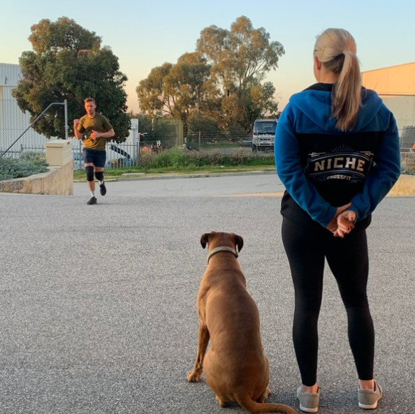 Coach and the gym dog watching a member finish a run outside the gym